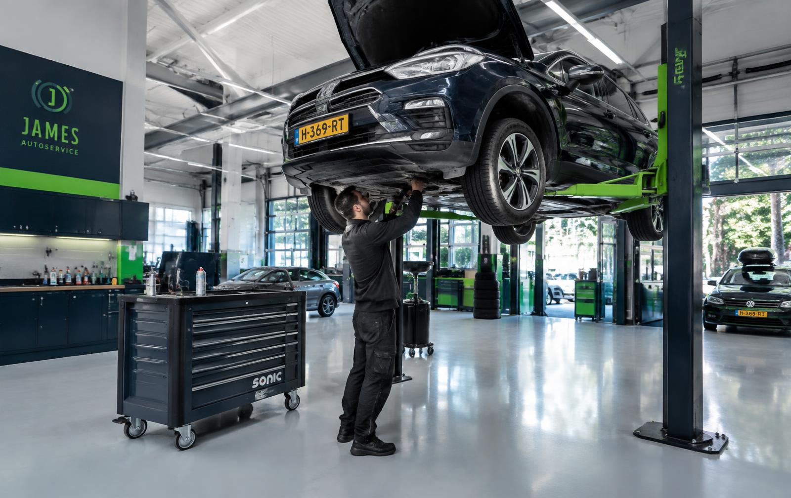 Moderne autogarage met een auto op de brug en een monteur aan het werk